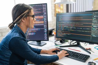 Woman with two monitors coding