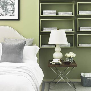 green bedroom with storage and bed lamp
