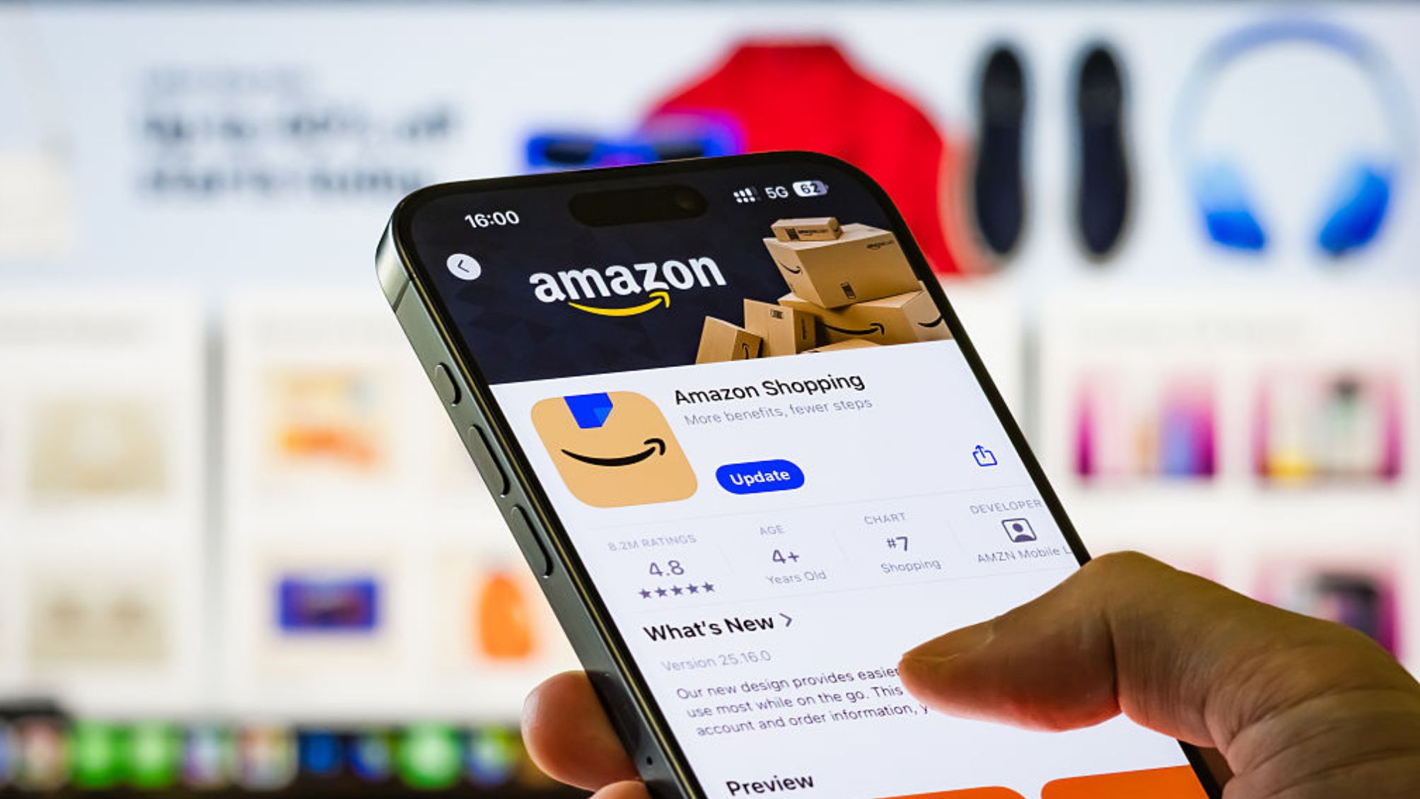 A person holds a smartphone showing the Amazon Shopping app page in the Apple App Store.