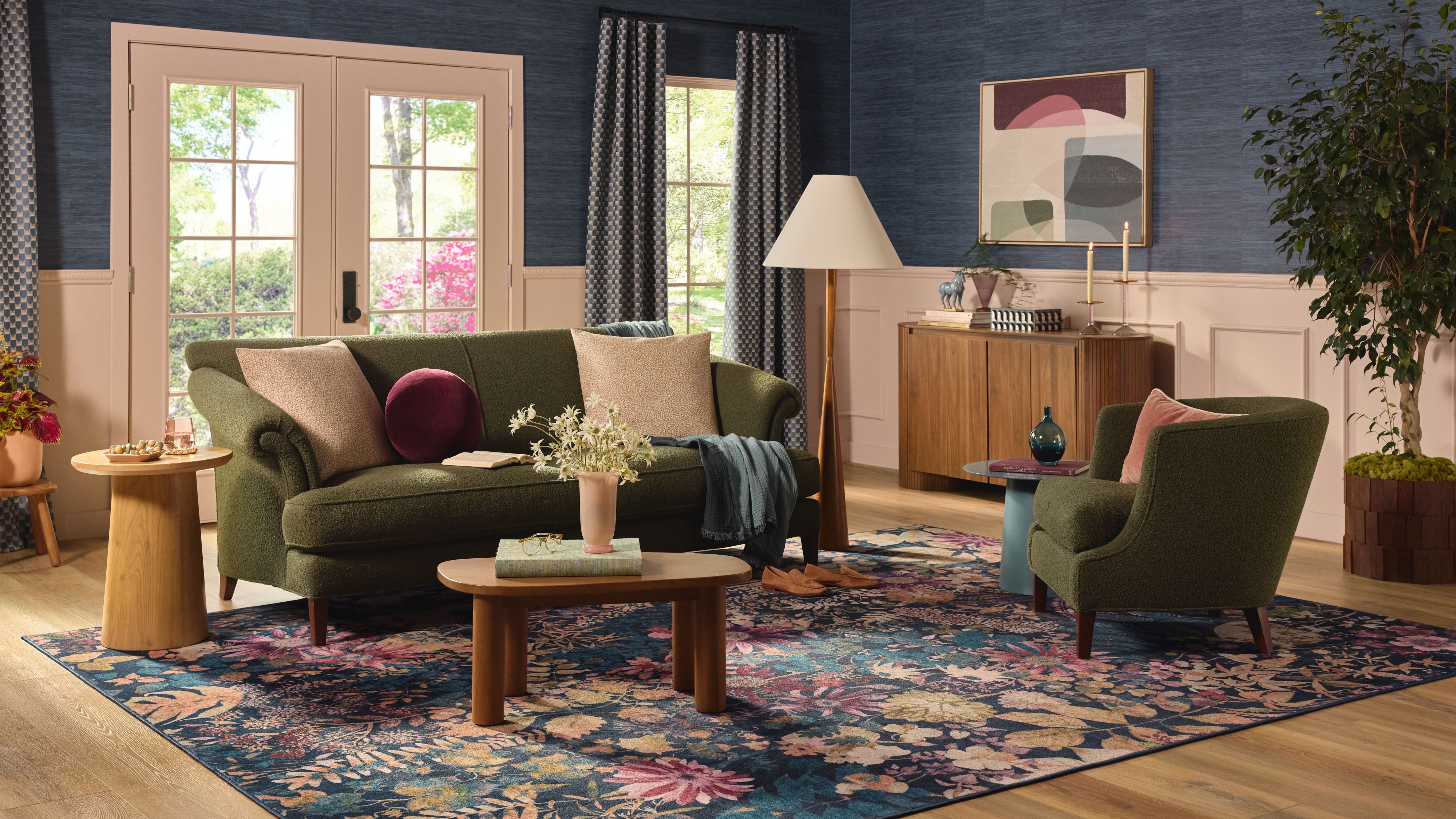 Jewel-toned living room featuring verdant green seating furniture, a wooden coffee table, and a floral, large-scale floral print rug