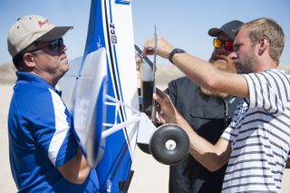 Derek Abramson, Justin Hall and Alexander Flock position the Prandtl-M glider aircraft onto the Carbon Cub that drops it from an altitude of 500 feet (150 meters).