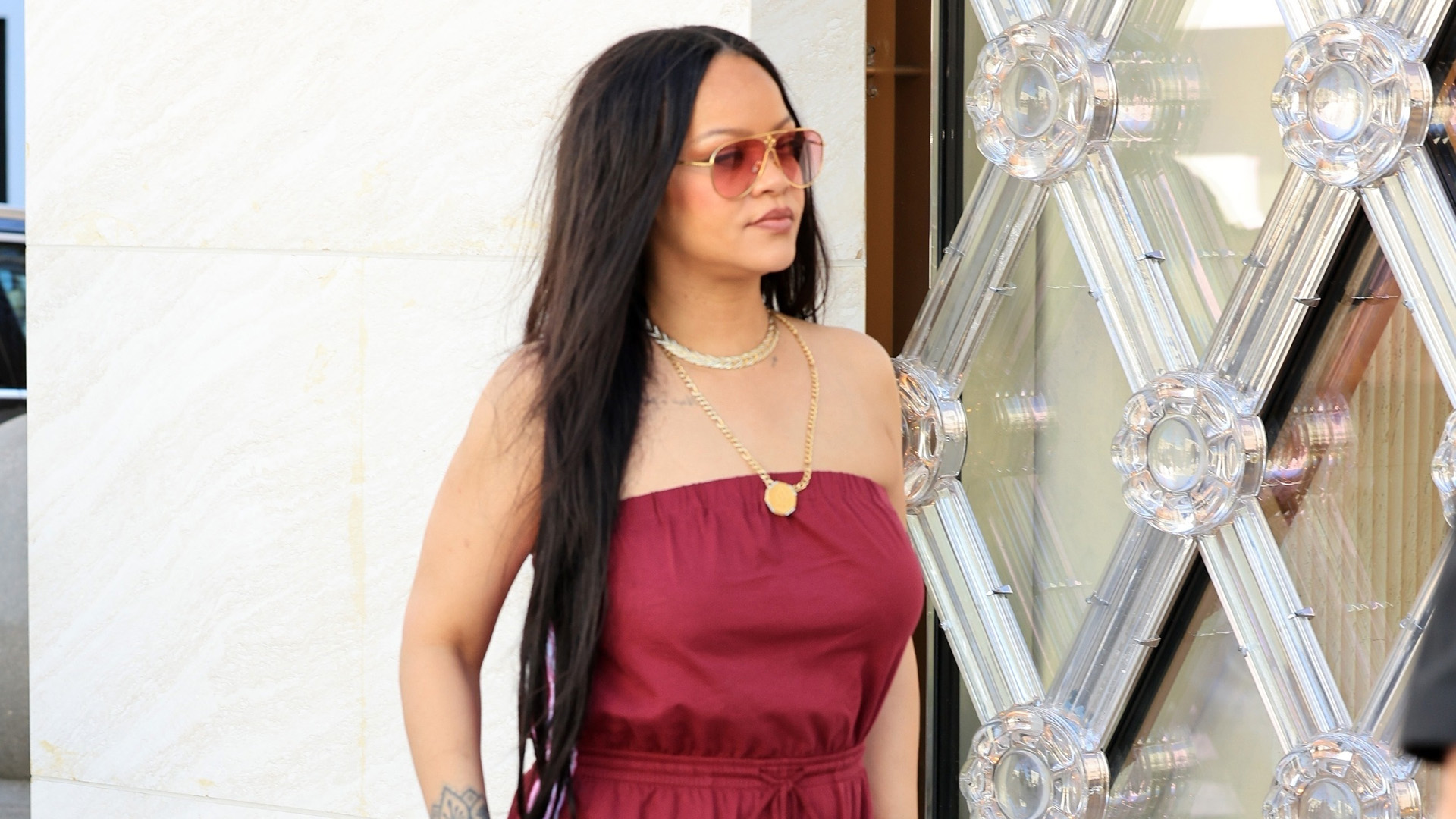 Rihanna wearing a burgundy strapless top and track pants with Nike x Jacquemus Moon Shoes in pink