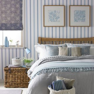 A white and blue bedroom with a wall covered in a striped wallpaper