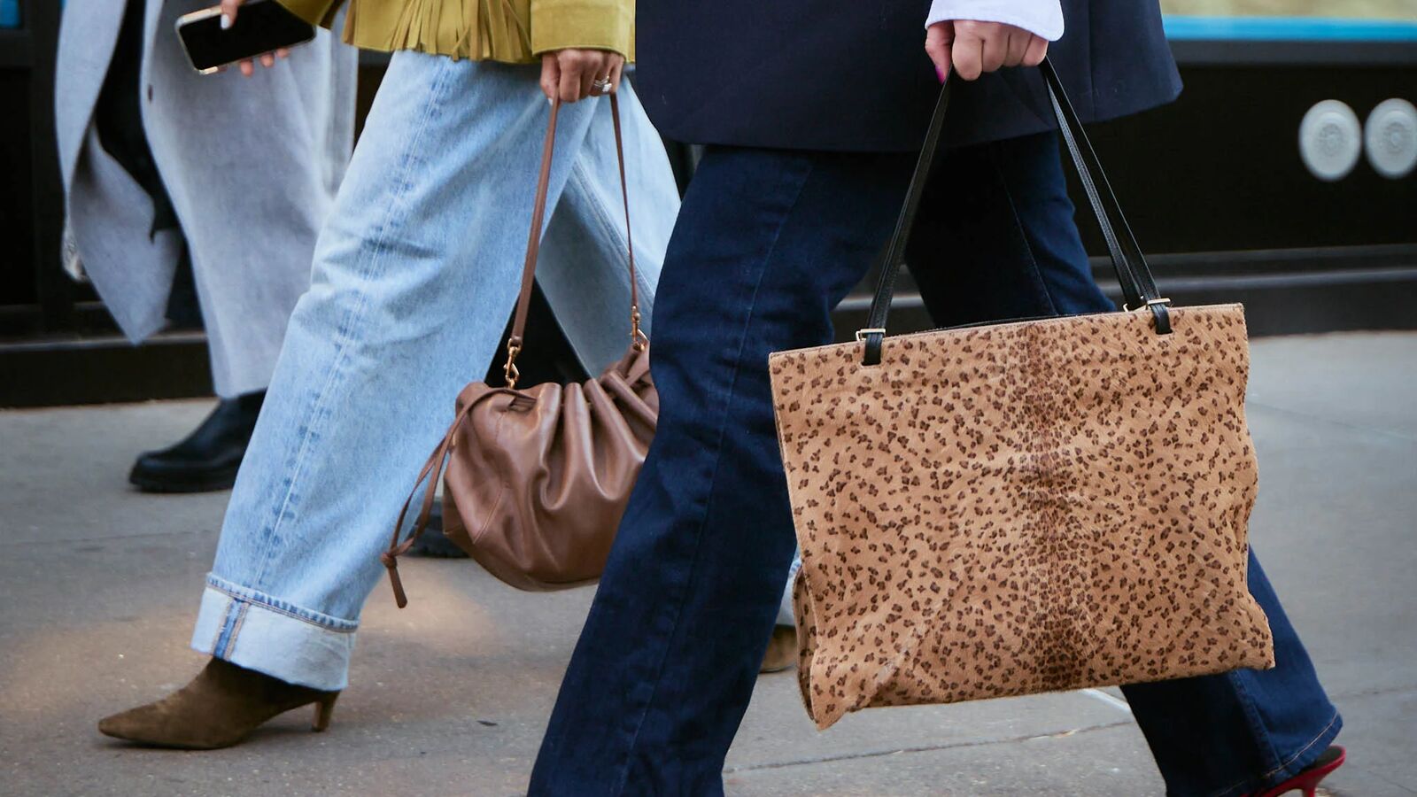 Women are walking while wearing jeans, jackets, and handbags