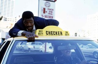 Carl Weathers as Lt. Jericho "Action" Jackson holds onto the roof of a taxi cab speeding down the street in Action Jackson