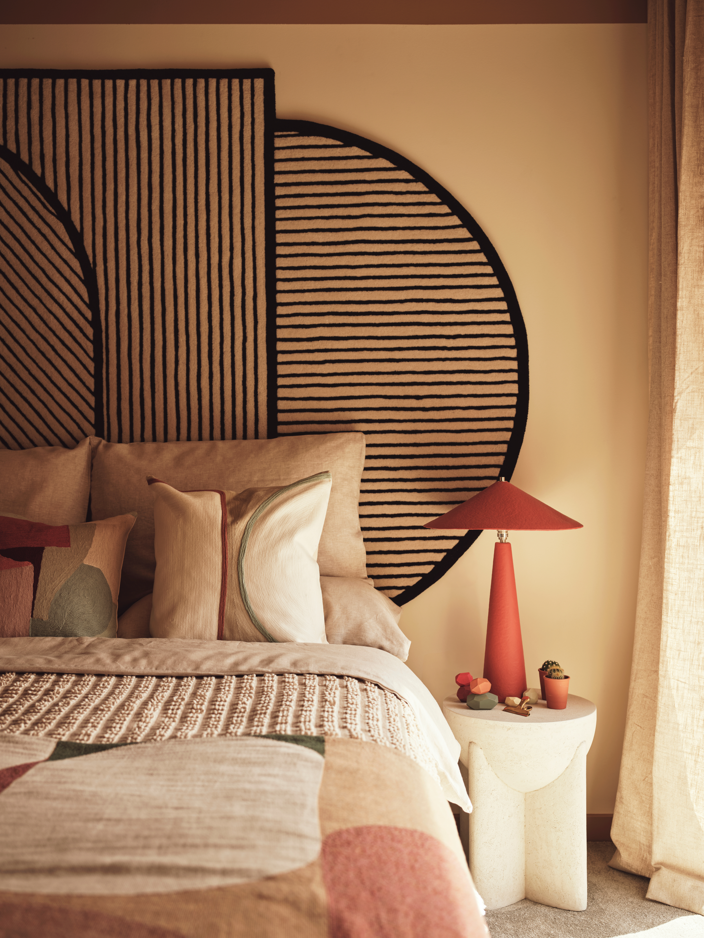 Beige bedroom with geometric beige and black rug as headboard