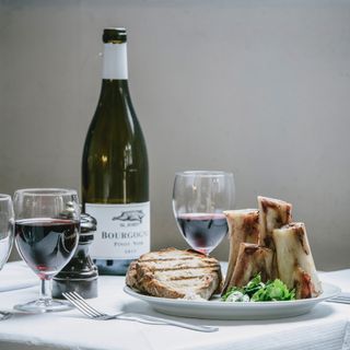 St John Bourgogne Pinot Noir with 2 glasses and a plate of bone marrow and toasted sandwich. Courtesy of St John