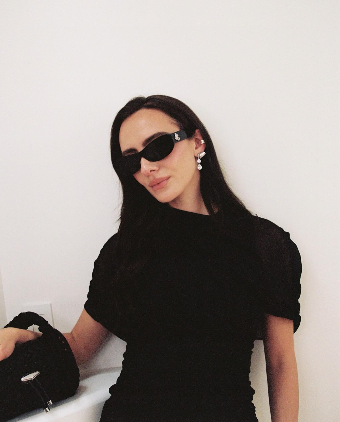 A woman wearing a black dress and black sunglasses