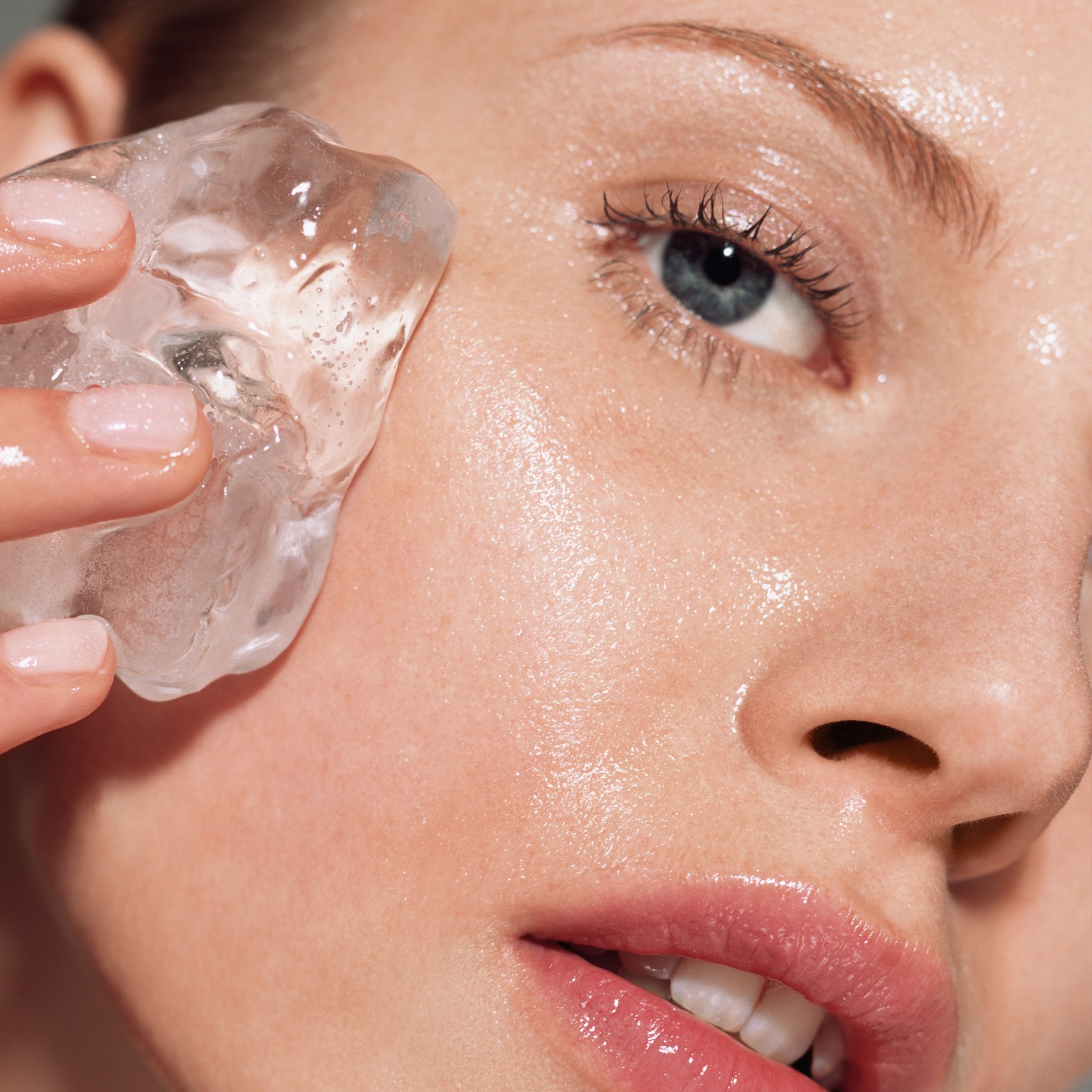 A woman rubbing an ice cube on her face