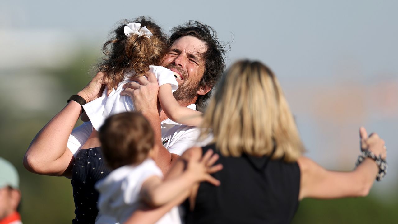 An emotional Nacho Elvira hugs one of his daughters as his wife, holding their other daughter, runs onto the 18th green to greet him at the 2026 Dubai Invitational