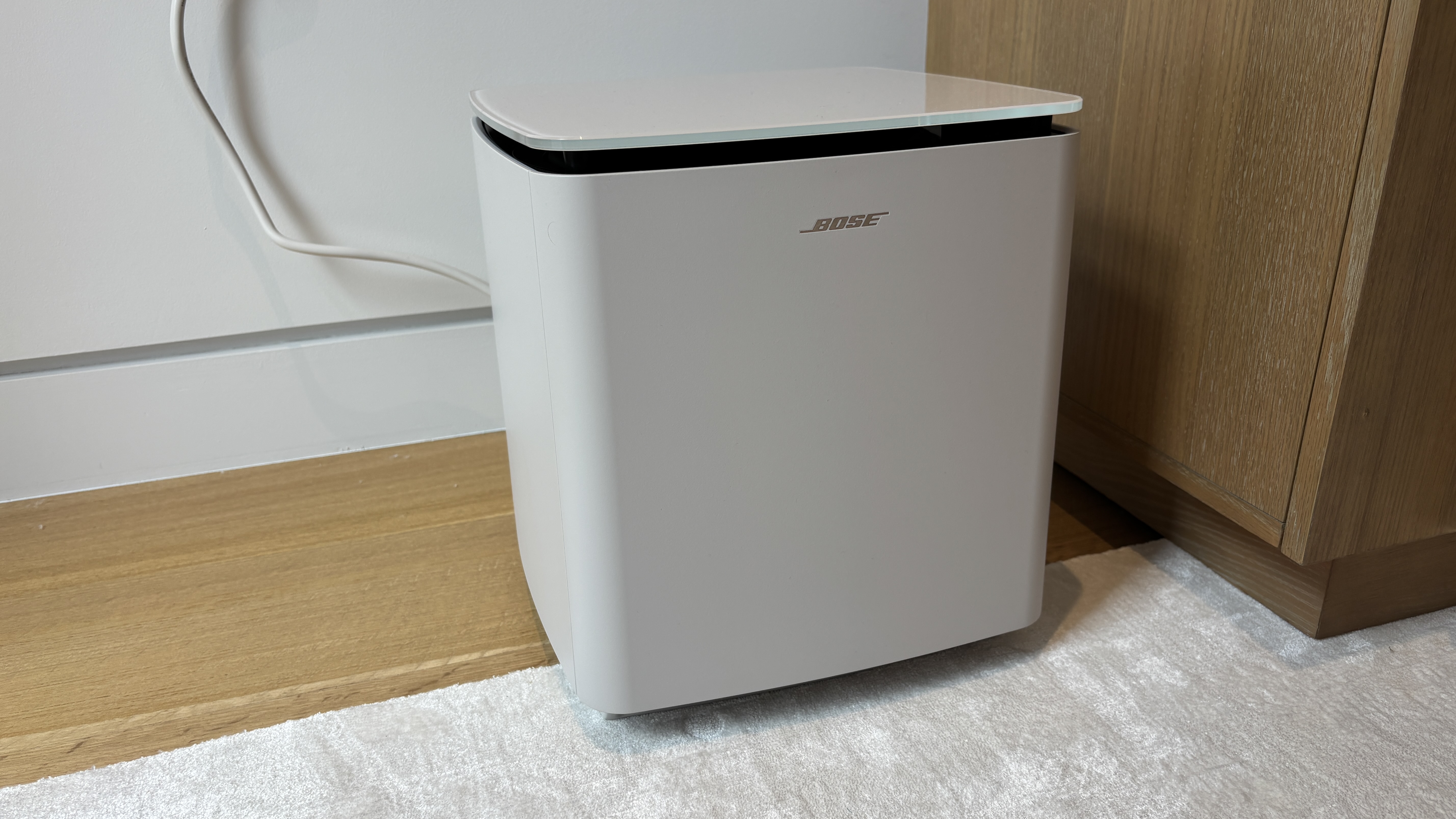 Bose Lifestyle Ultra Subwoofer in white smoke sat on the floor next to some furniture
