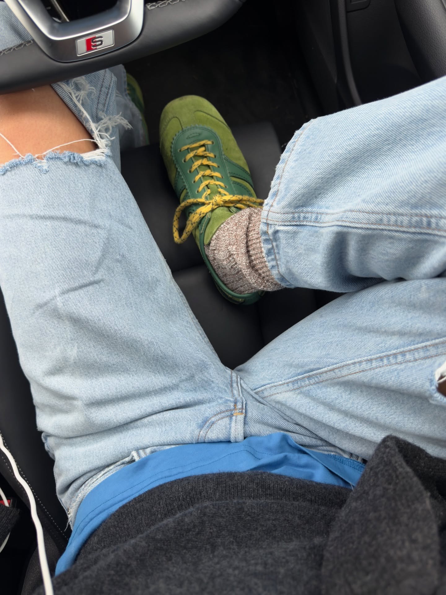 Fashion person smythsisters wears a trending trainer brand 2026. She wears green Dries Van Noten trainers. She wears them with blue ripped denim jeans, a blue tee and grey jumper. This image was recently taken from her Instagram.