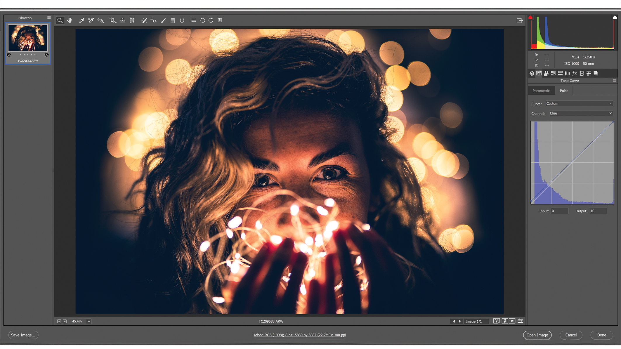A Photoshop window with editing menus, an image in the center showing a person with wavy hair surrounded by soft, golden bokeh lights that create a warm and dreamy atmosphere