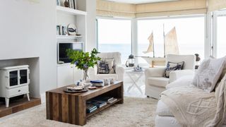 Coastal white living room with wooden coffee table and armchairs demonstrating ho to make a small living room look bigger