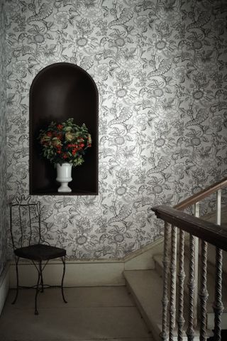 Hallway with black and white patterned wallpaper and an arched alcove painted black