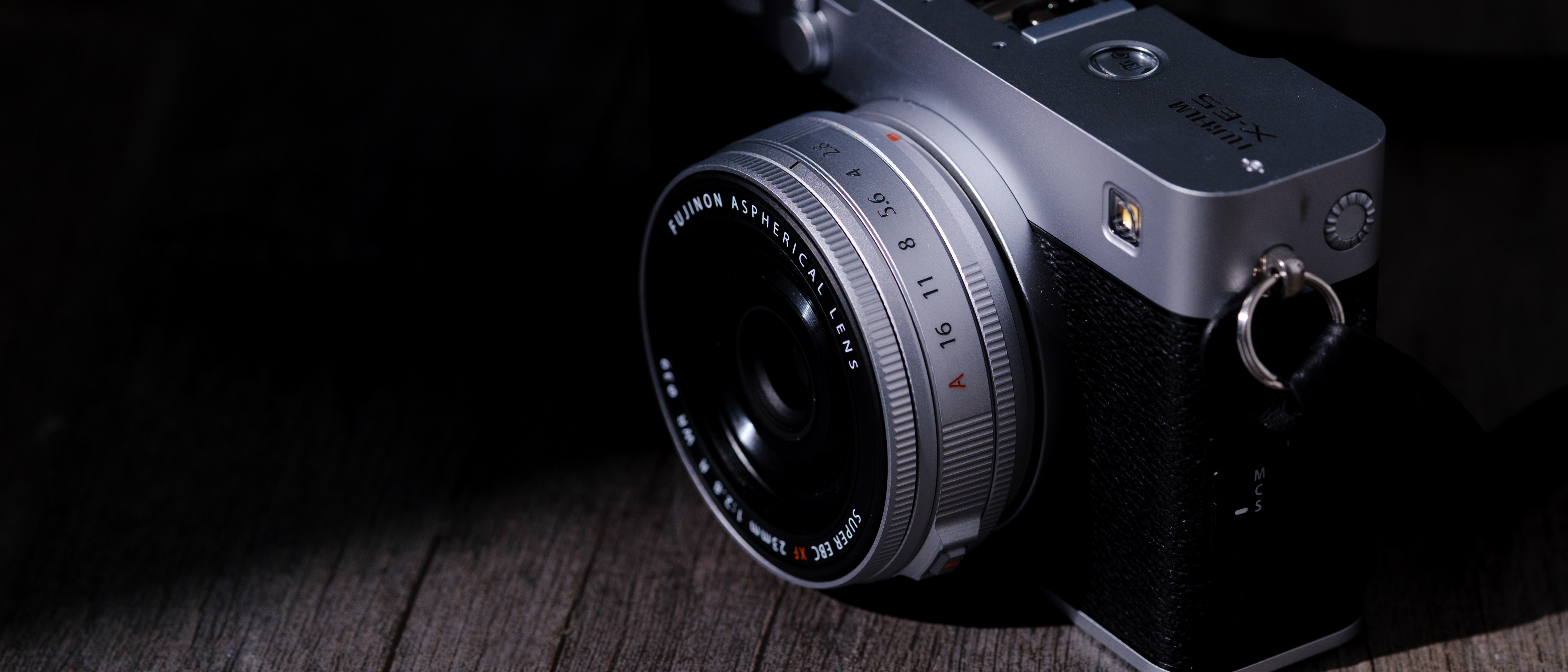 The Fujifilm XF 23mm f/2.8 R WR on a gray wood-like surface