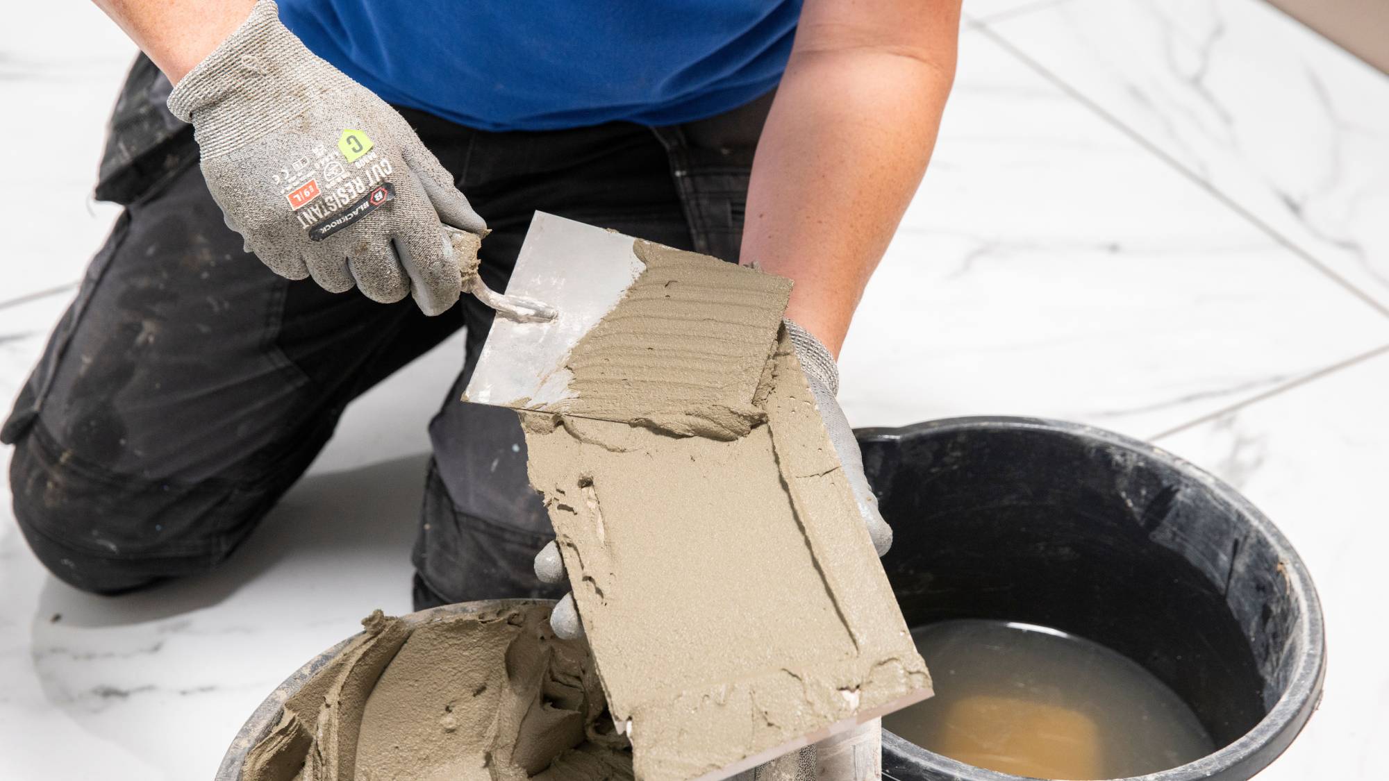 DIYer spreading tile adhesive on tile
