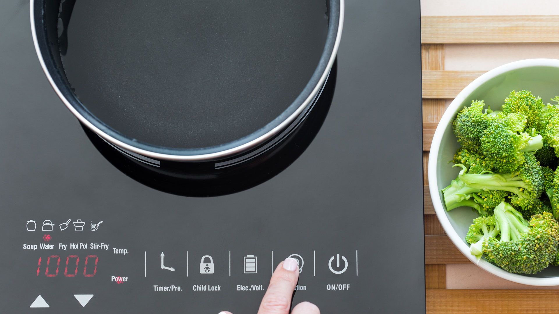 Woman using controls on an induction hob to show how to use the best induction pans