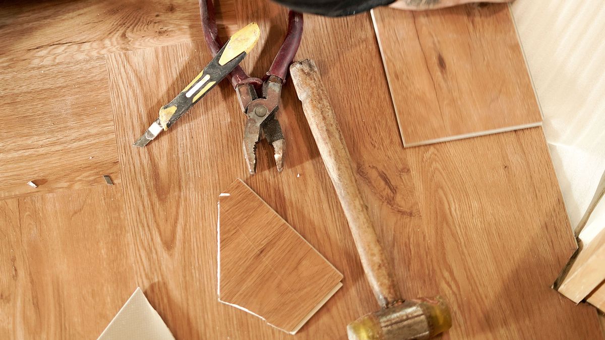 Various flooring tools next to broken laminate on top of laminate floor