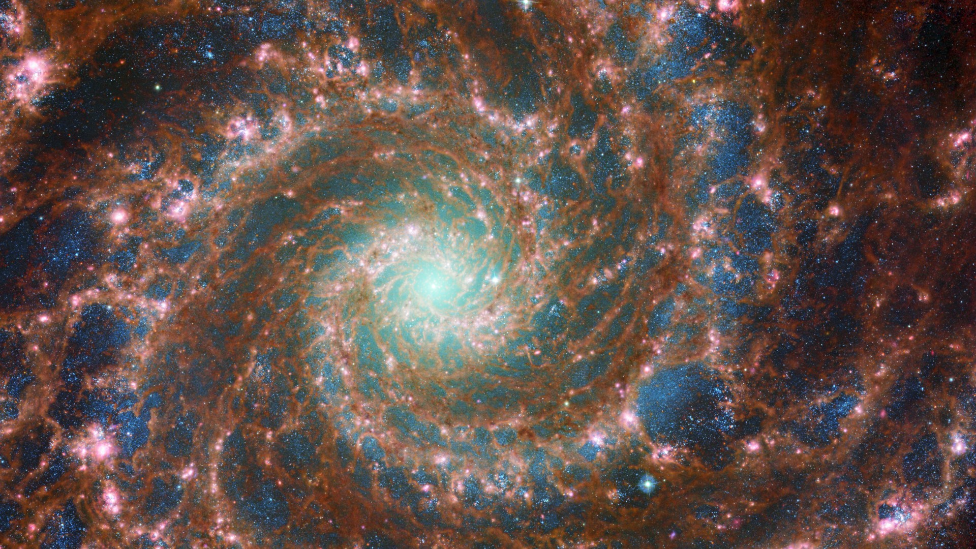 A combined optical / mid-infrared image featuring data from both the Hubble Space Telescope and the James Webb Space Telescope.  It is in a spiral pattern.