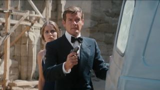 Roger Moore stands with gun drawn, while Barbara Bach stands behind him in The Spy Who Loved Me.