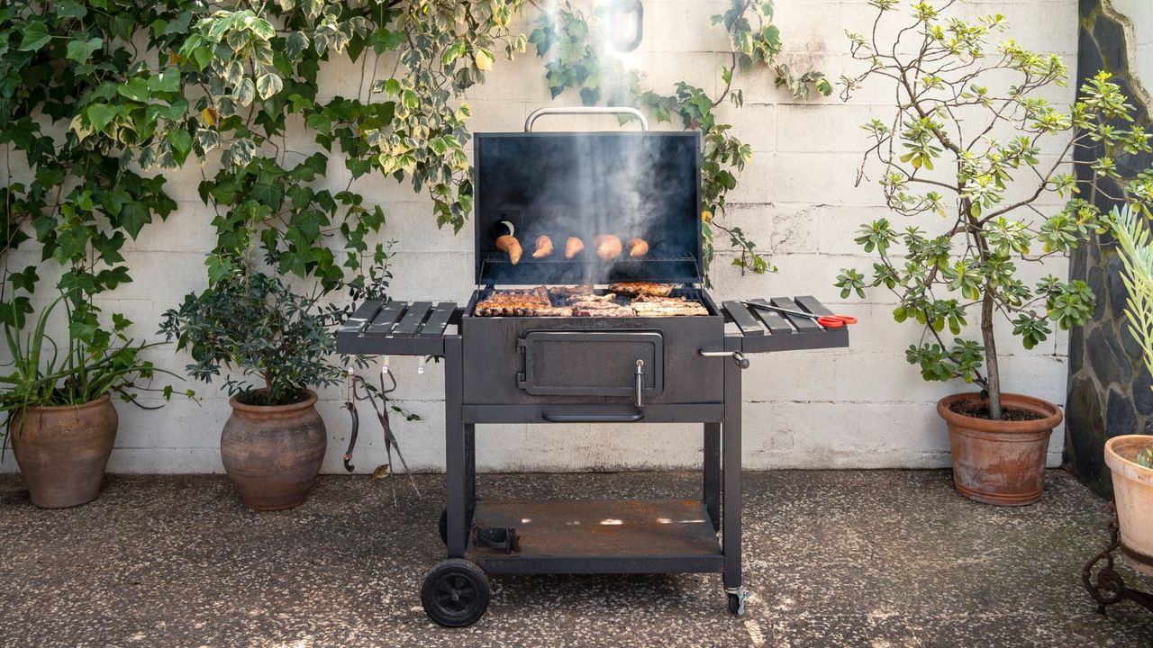 A charcoal grill making ribs and potatoes