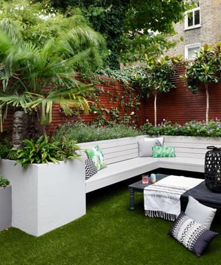 An example of the best trees for a small garden, with white L-shaped outdoor sofa.