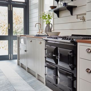 country kitchen ideas, country style kitchen with grey herringbone floor, black Aga, cream Shaker units, brass taps