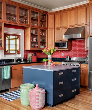 kitchen with wooden cabinets, blue island, wooden floor, red backsplash and stained glass window
