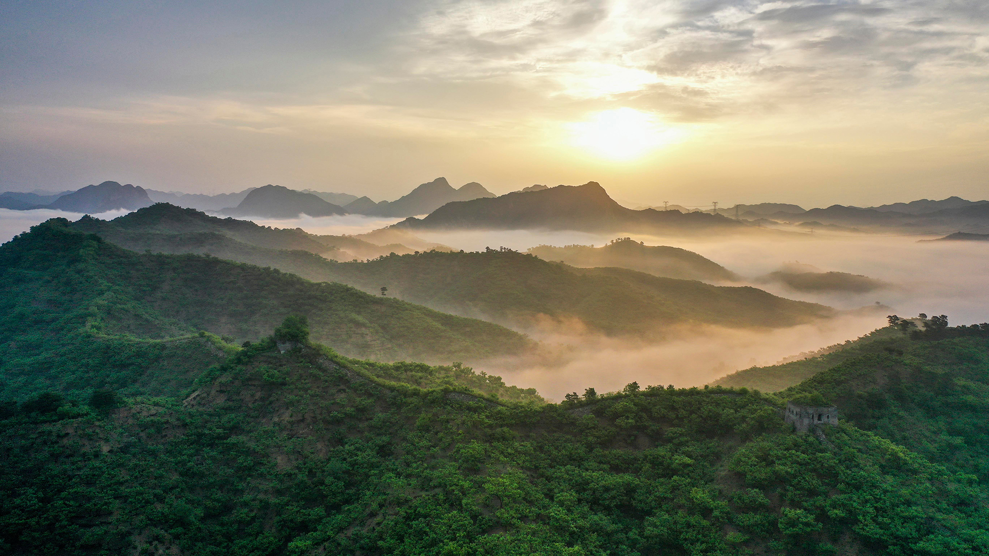 Morning mist clings to the forested hills surrounding a section of the Great Wall in Zunhua City, northern China
