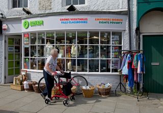 Senior woman outside Oxfam charity shop, England UK