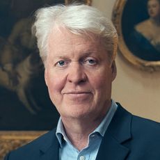 Charles Spencer in a navy jacket standing in front of paintings