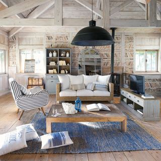 Coastal-style living room with blue rug and bare floorboards