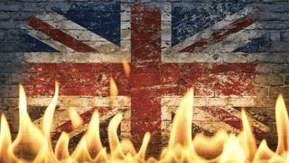 The British flag on a brick wall behind flames