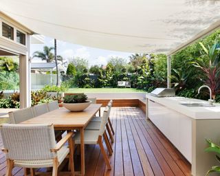 An decked outdoor kitchen with a canvas shade