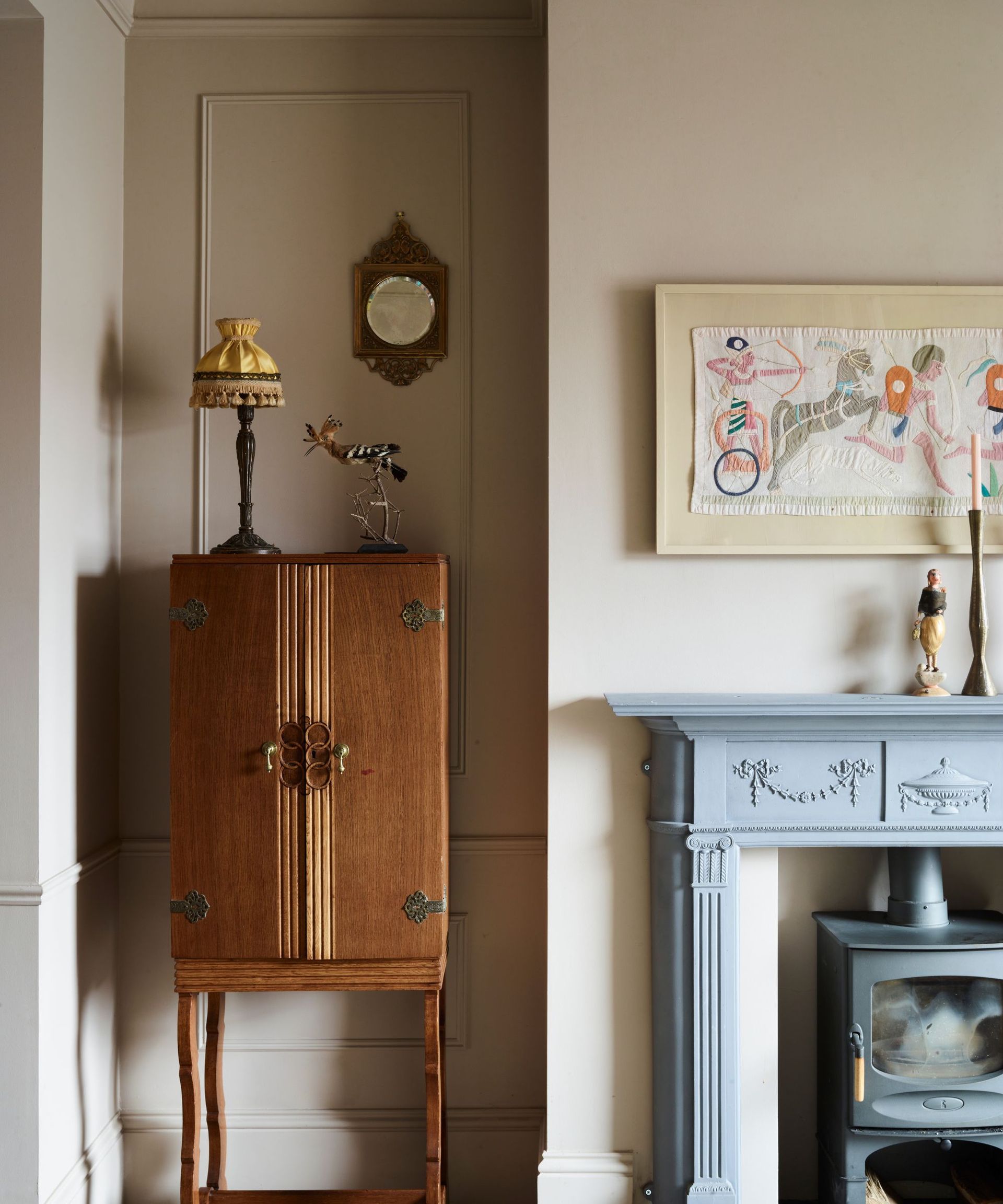 Living room with wood antique bar cabinet and blue painted fireplace with tapestry picture hanging above
