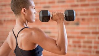 a woman lifting a dumbbell above her shoulder