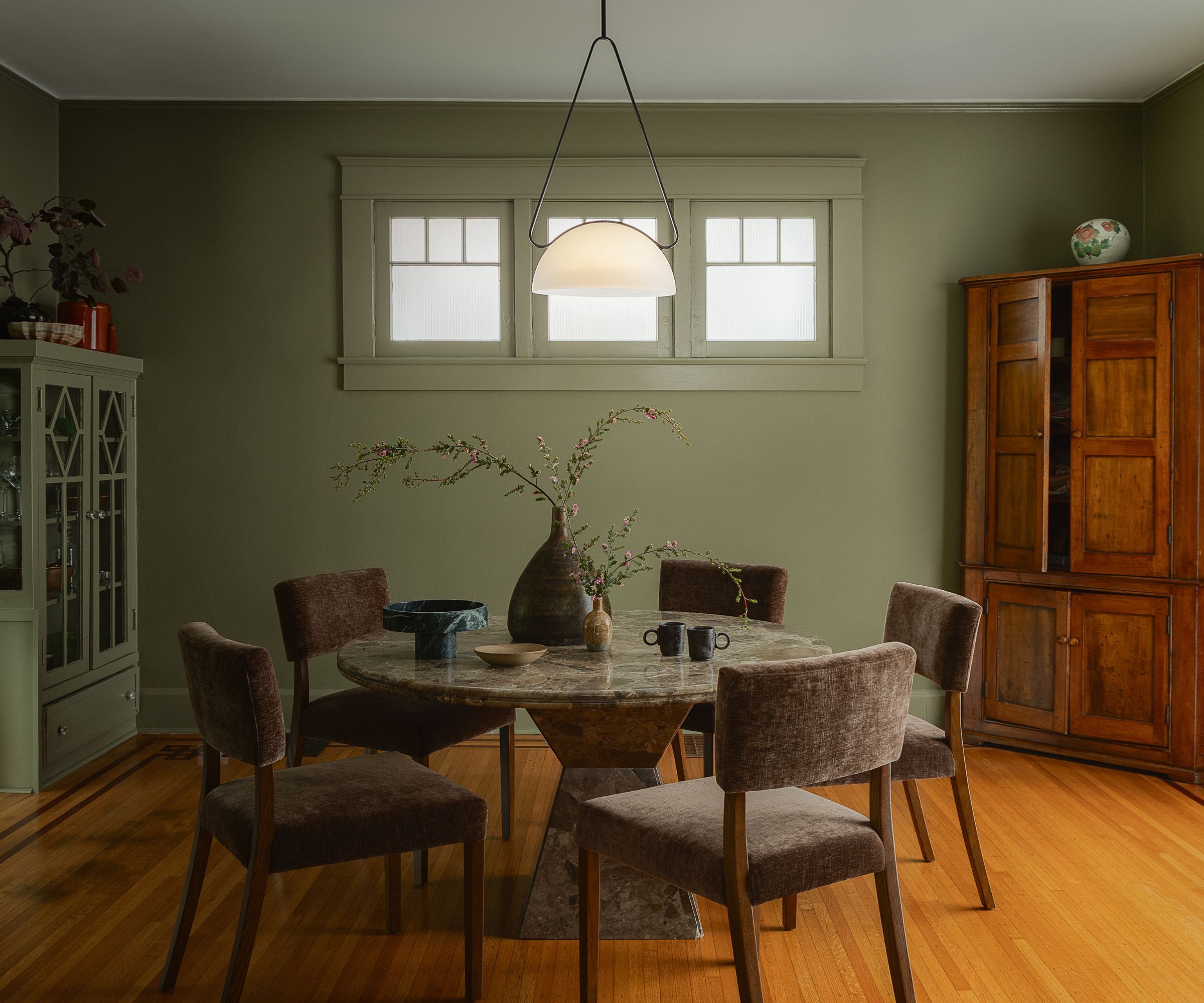 A green dining room with a round wooden table