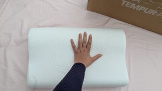 A white curved design pillow next to a cardboard box