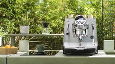 One of the best coffee makers on the market, the Faemina in silver sat on a green countertop outside