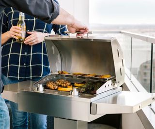 A Coyote 18-Inch Electric Grill cooking on a balcony