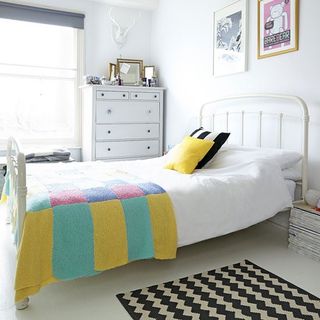 bedroom with photoframe on white wall and white bed with pillows