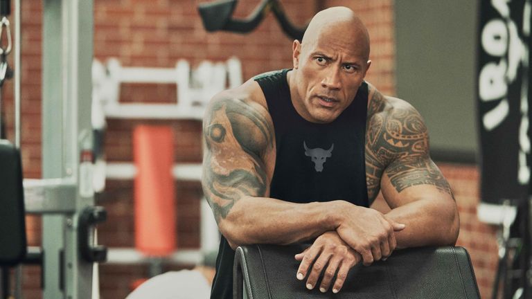 Dwayne Johnson looking stern in his home gym wearing an Under Armour tank top