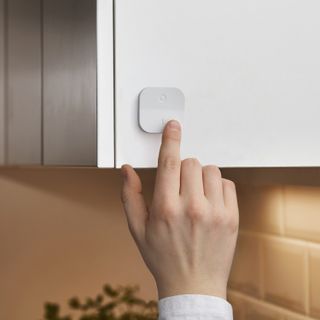 A finger controlling a wireless dimmer switch attached to a cabinet