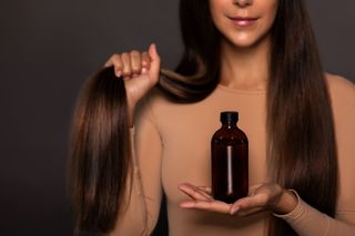 a woman with brunette hair holding a bottle of walnut oil