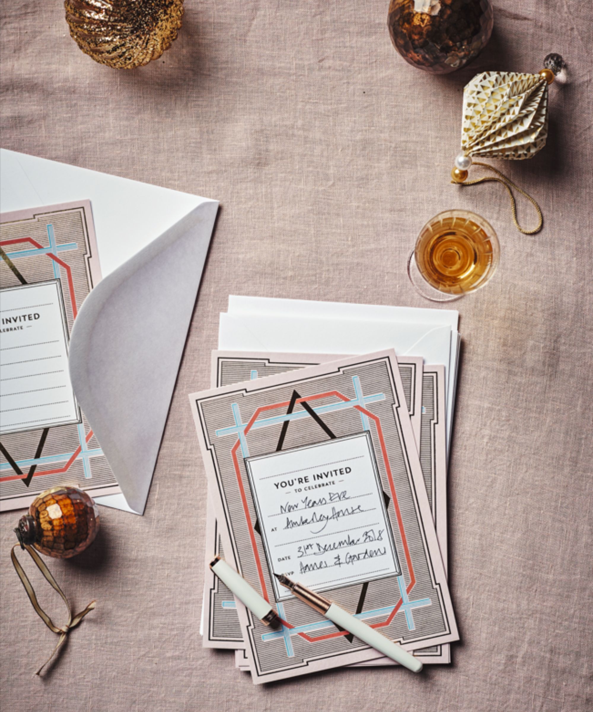 Festive invitation with baubles, a drink and a pen