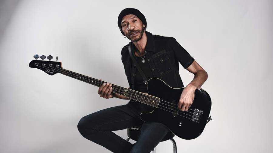 Dug Pinnick sitting on a stool holding a bass guitar