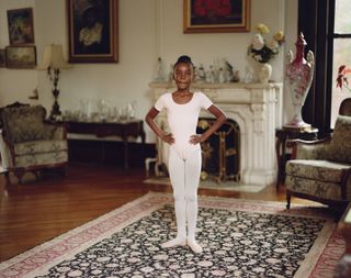 a little girl in a ballet leotard stands in an ornate living room with her feet in first position in a photo from the book things shouldn't be so hard