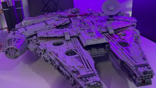 The fully-built Lego UCS Millennium Falcon on a table, bathed in purple light