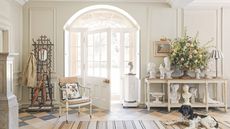 A traditional entryway painted white with a collection of patinated antique and vintage items displayed